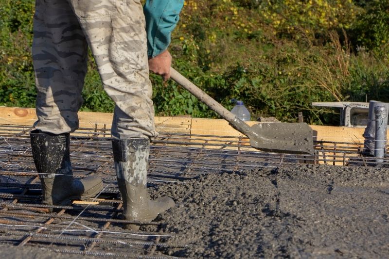 concrete contractor using a shovel to a concrete mixture