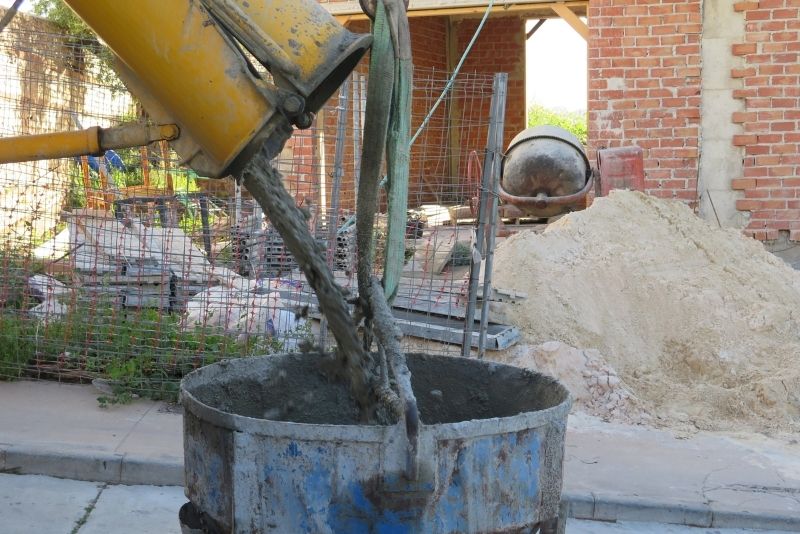 yellow coloured concrete mixer pouring concrete in a blue big drum