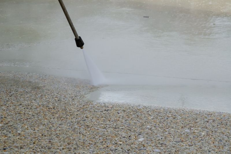 pouring water from a hose into a exposed aggregate concrete driveways