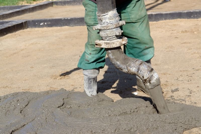 concrete driveway contractor pouring concrete mix on the ground