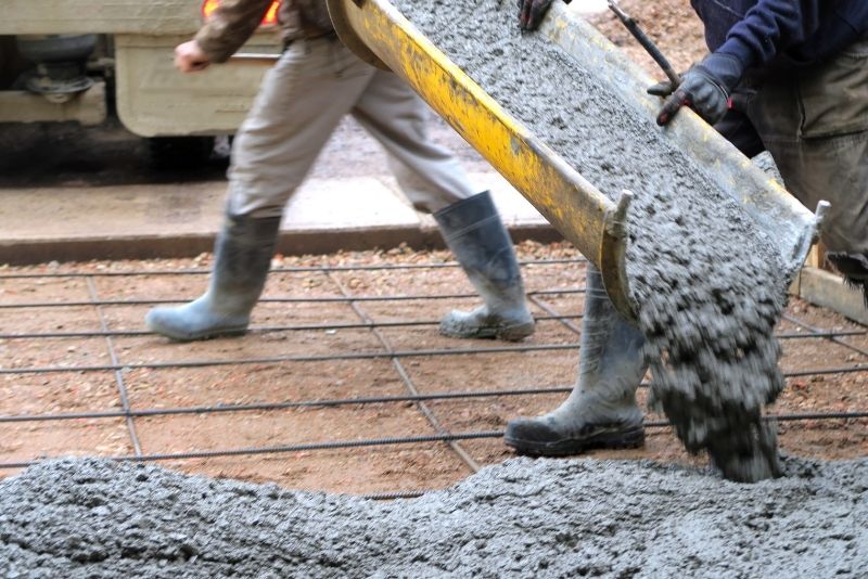 concreters pouring concrete mix in the ground foundation